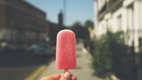 Man-holding-ice-lolly-point-of-view-walking-through-city